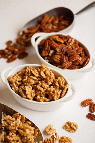 there are plates of walnuts and pecans on the white table