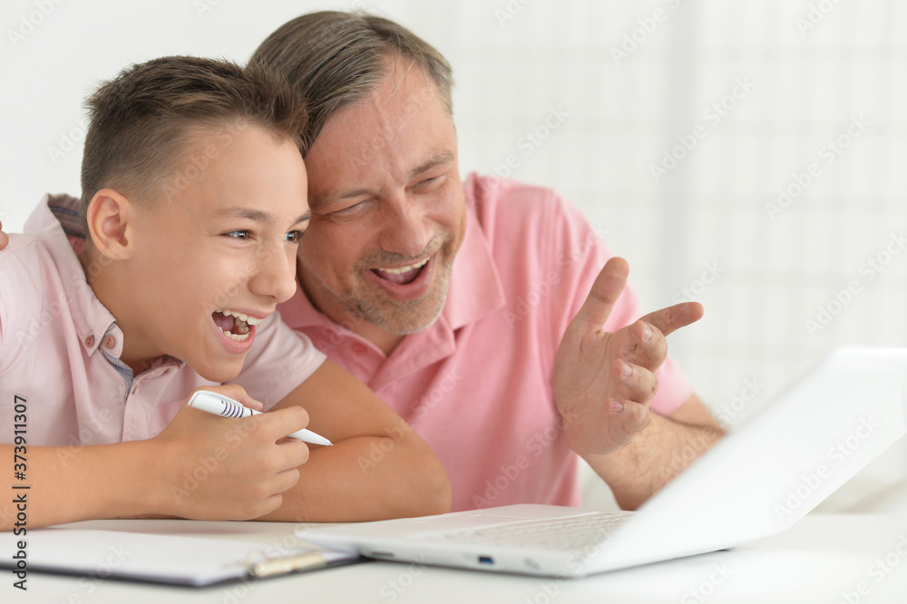 Close up portrait of son and father using laptop at home Close up portrait of son and father using laptop at home