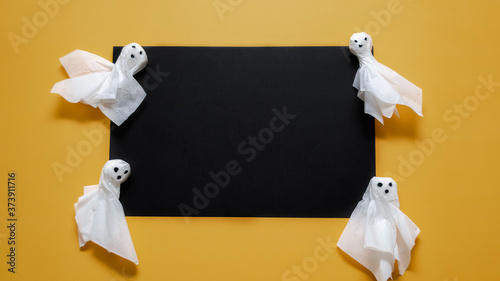 Homemade Halloween ghosts on a black and yellow background. Halloween concept. Place for inscription