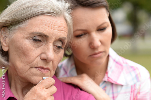 Close up portrait of sad senior woman with adult daughter