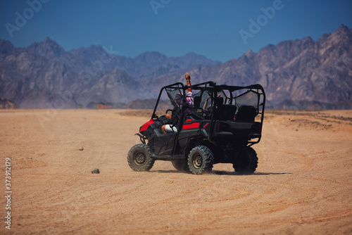 excited people are driving a buggy car through the desert. extreme tourism adventures