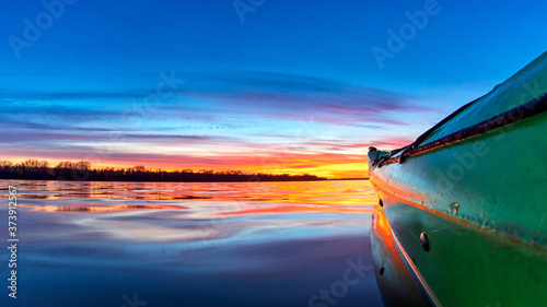 Side of a green kayak at sunset over an autumn river. Colorful sunset over water