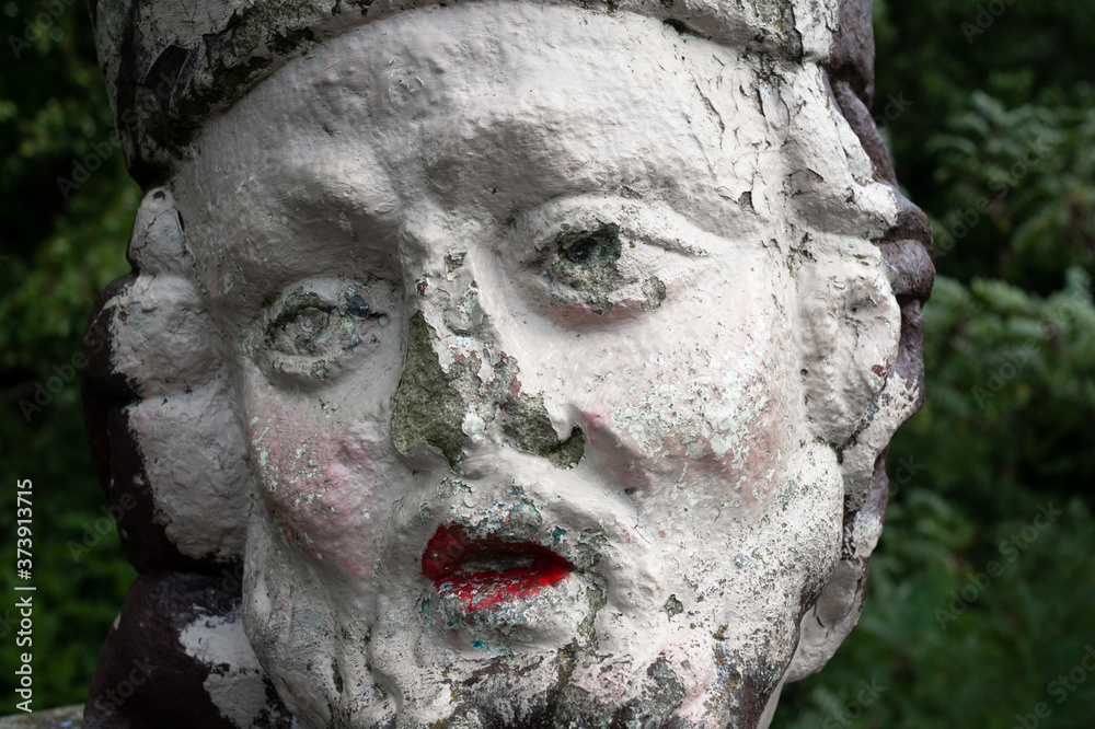 Old and aged statue of Jan Nepomucky / John of Nepomuk. Sculpture is ruined, shabby and dilapidated. Vandalism - face has colored lips by lipstick.