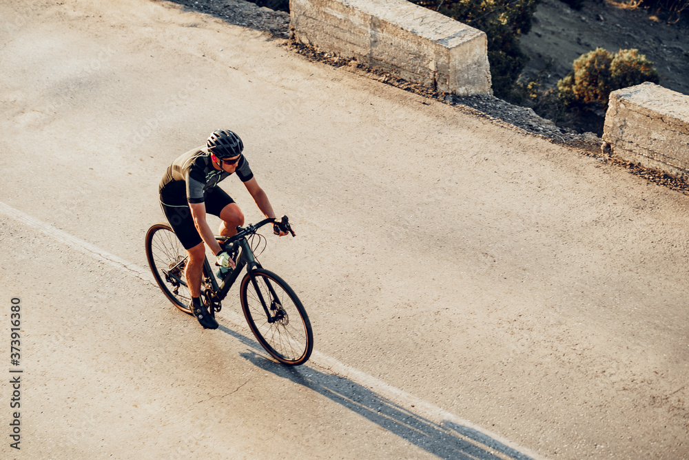 Naklejka premium Professional cyclist on a mountain road at sunrise