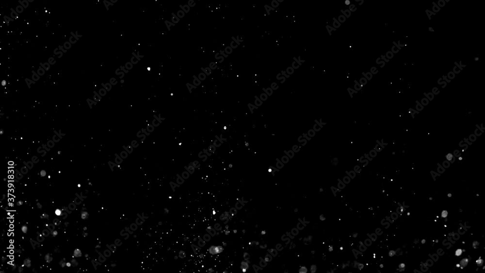 Dust particles sparkling on black background with white light bokeh effect