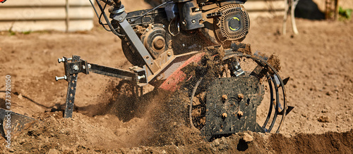 Fotografie Gardener cultivate ground soil with tiller tractor or rototiller, cutivator
