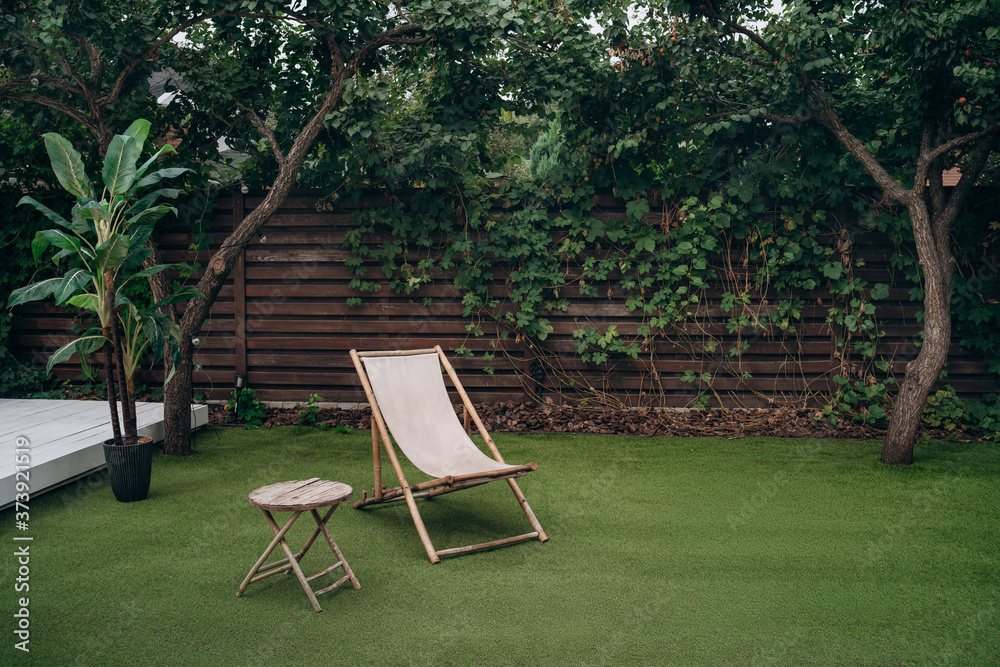 Lounge zone. Wooden lounge chair and table on lawn grass in a garden. Rest relaxation place. rest concept Lounge zone. Wooden lounge chair and table on lawn grass in a garden. Rest relaxation place. rest concept