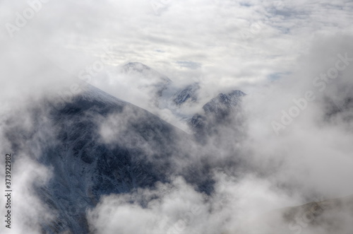 Natural background. Clouds float between high mountains. Soft focus. Selective focus on the mountain. © Sergei