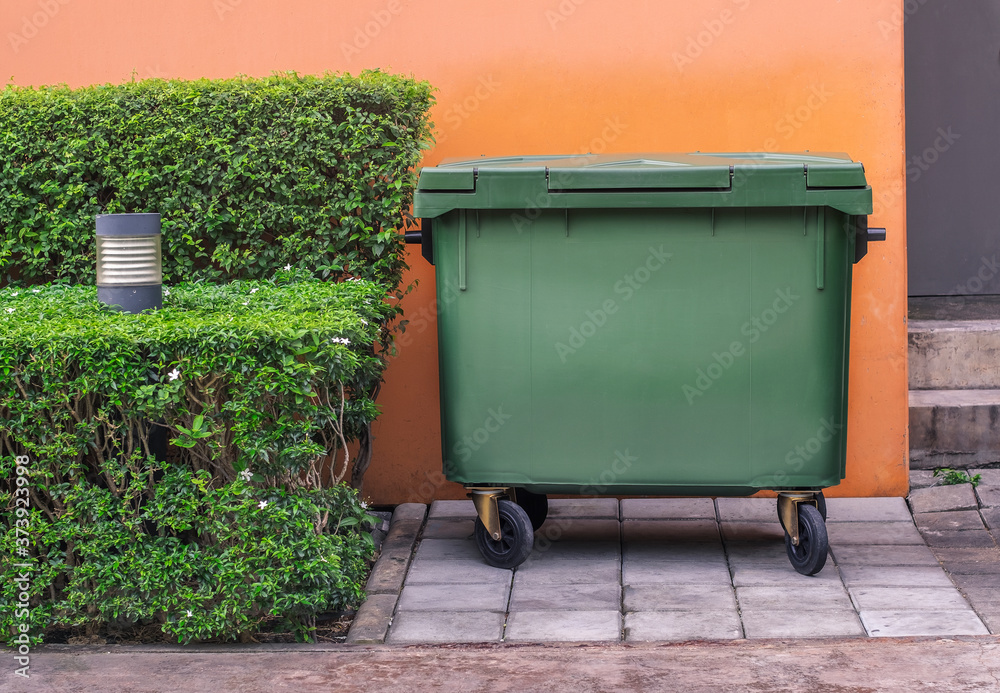 old garbage container is located near the wall. old garbage container is located near the wall.