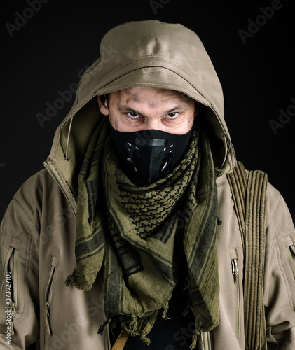 Young handsome man wearing black protactive face mask and jacket with hood on gray background photo