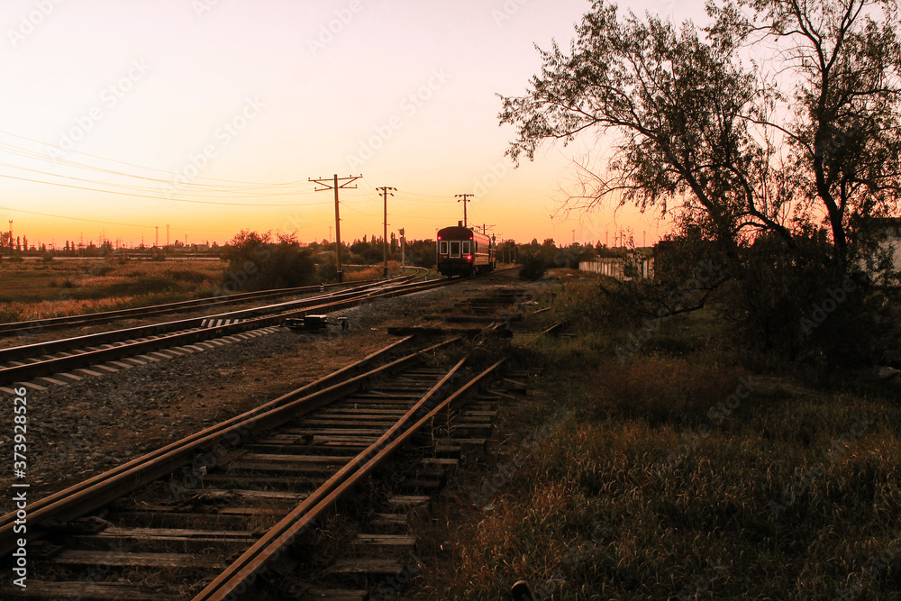 The train goes off into the distance. Evening in Dzhankoy, Crimea