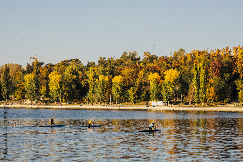 Young people are kayaking on a lake in beautiful autumn nature. Colourful trees. Young people are kayaking on a lake in beautiful autumn nature. Colourful trees.