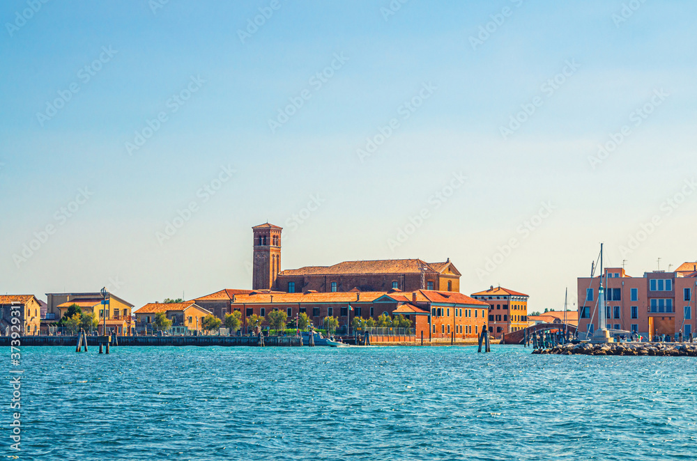 View from sea lagoon of Chioggia town cityscape with Saint Domenico catholic church and old buildings in historical centre, blue sky background in summer day, Veneto Region, Northern Italy