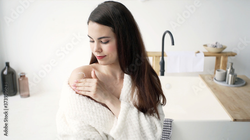 Young adult woman in bathrobe spending morning at bathroom