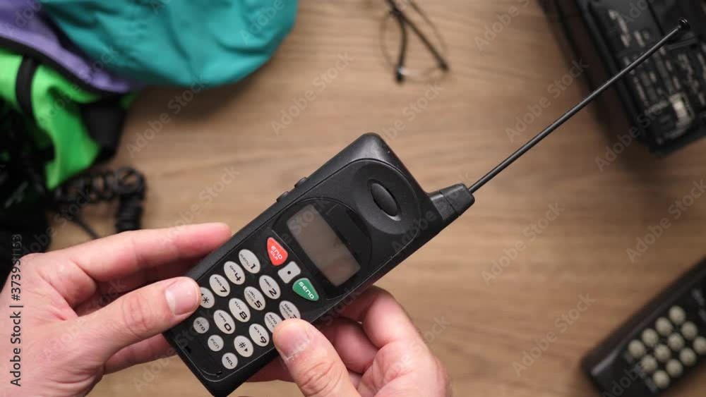 Using a retro cell phone from the 80s 90s. Top view from above over a retro 80s 90s desk.