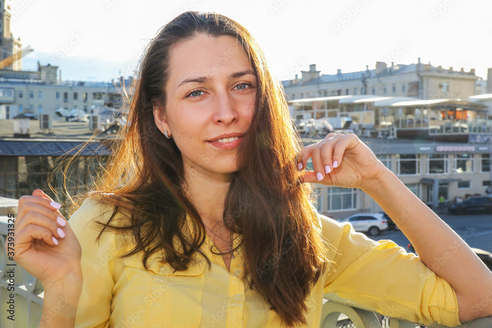 a young woman stands against the background of houses a young woman stands against the background of houses