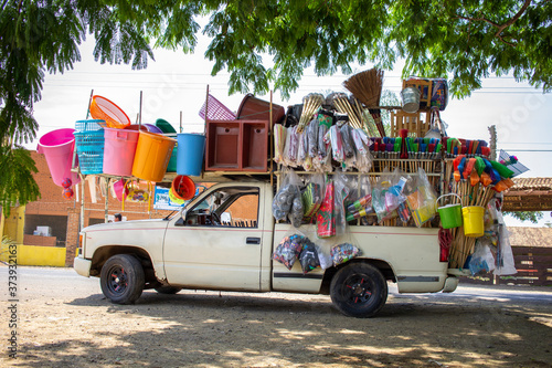Vendedor ambulante latino mexicano vehículo comercio informal negocio emprendedor comerciante portátil colorido escobas utensilios tianguis mercado photo