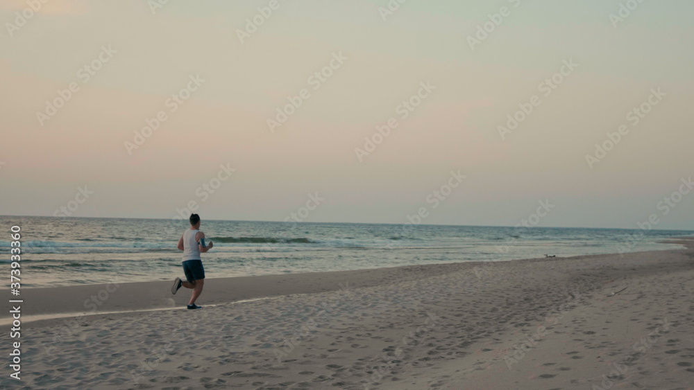 Athlete is Doing Sports, Running at Sea Coast and Jogging on Beach in Summer
