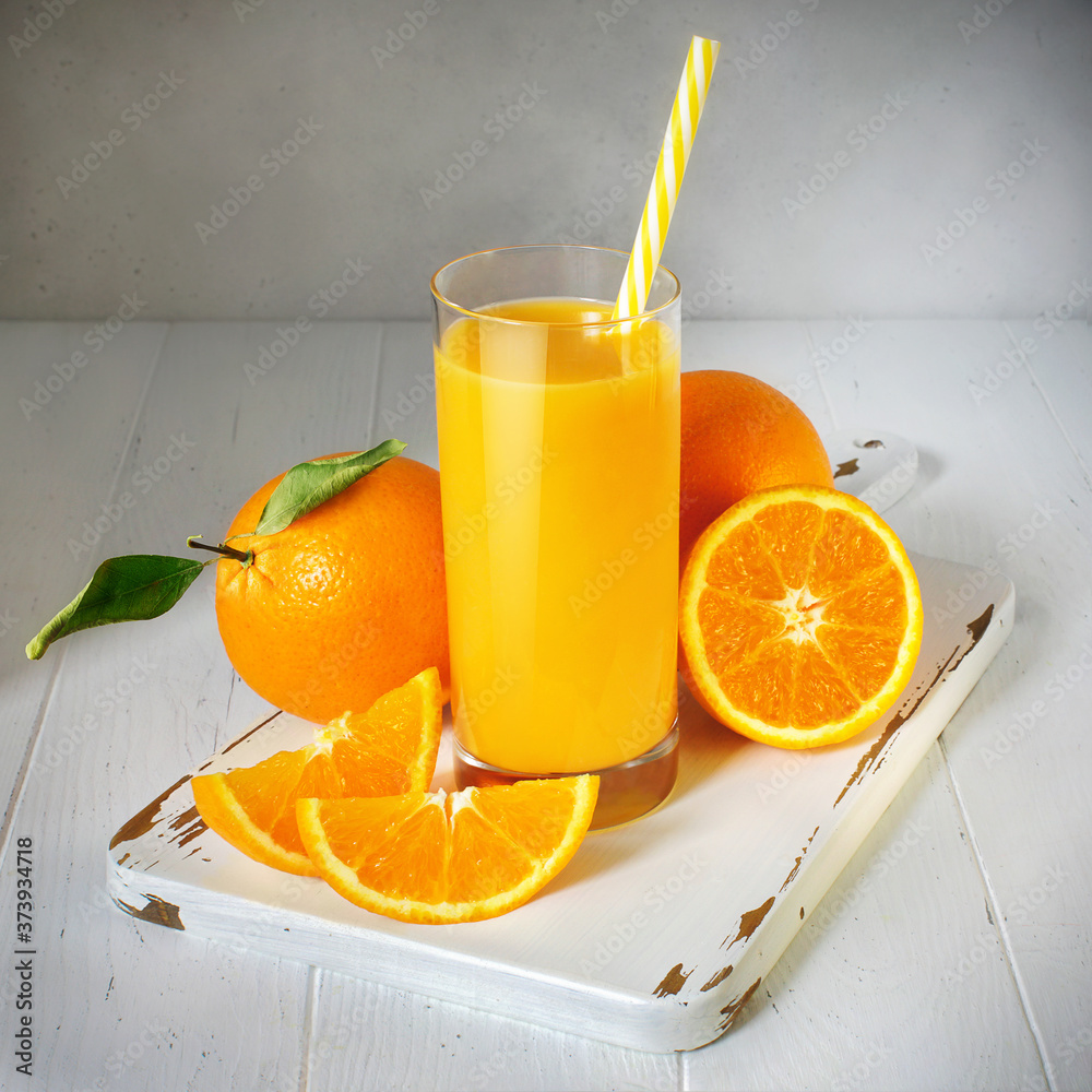 A glass of orange juice and fresh fruit on a white wooden table