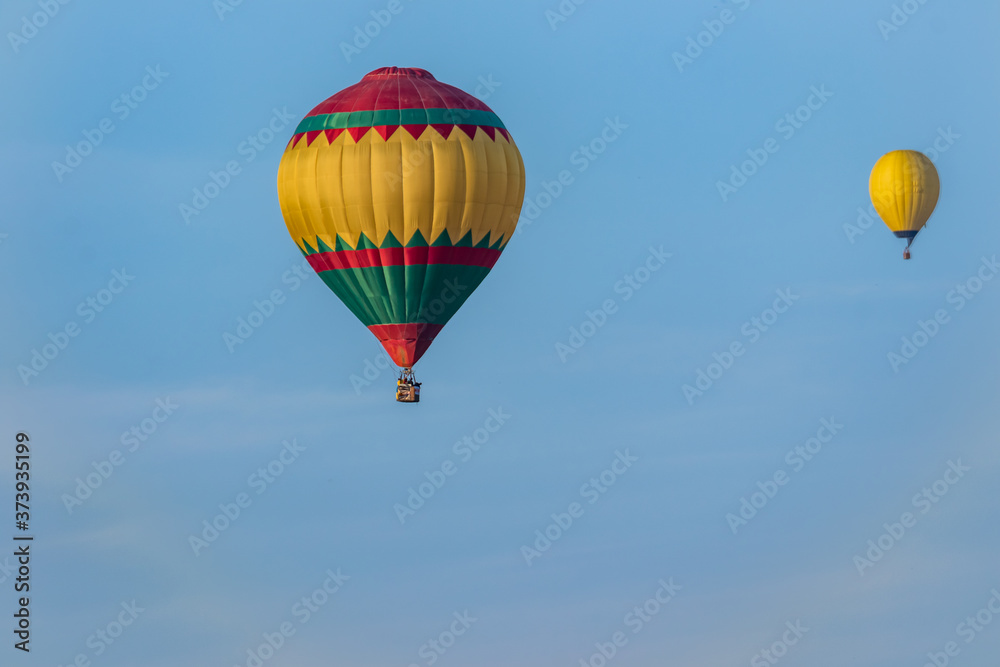 Fototapeta premium Two bright balloons in flight against a background of blue sky. Colorful balloons of watercolor painting float at different distances.