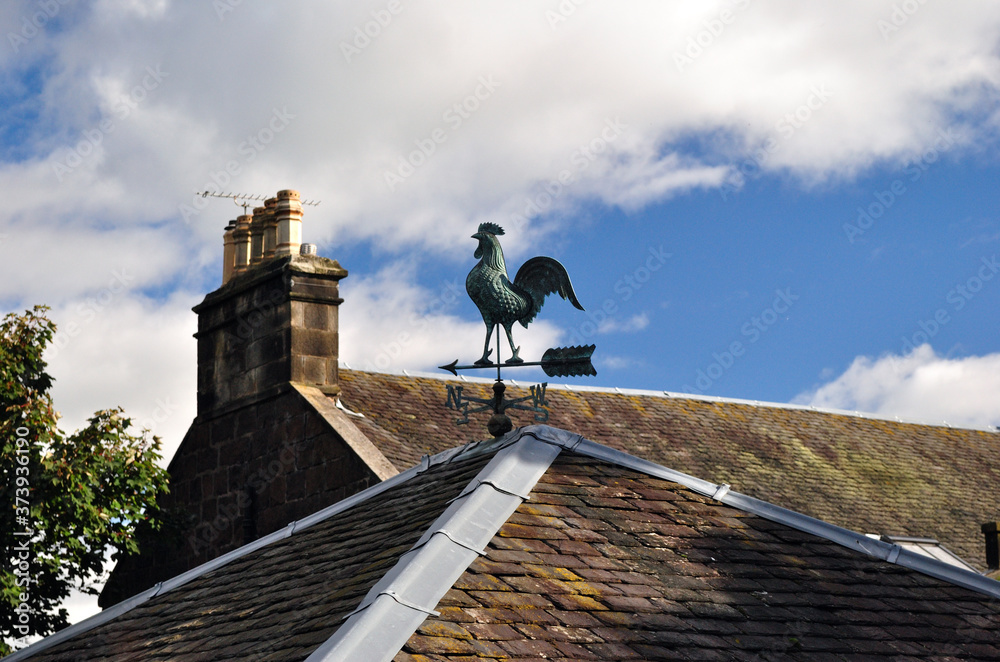 Roof with Rooster Weather Vane & Chimney against Blue Sky