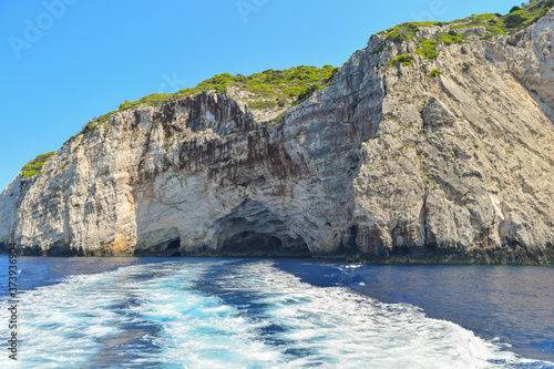 Fototapeta Naklejka Na Ścianę i Meble -  Gray rocks on the blue waters of the Mediterranean Sea in Greece. Motorboat traces on the water