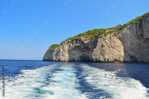 Gray rocks on the blue waters of the Mediterranean Sea in Greece. Motorboat traces on the water