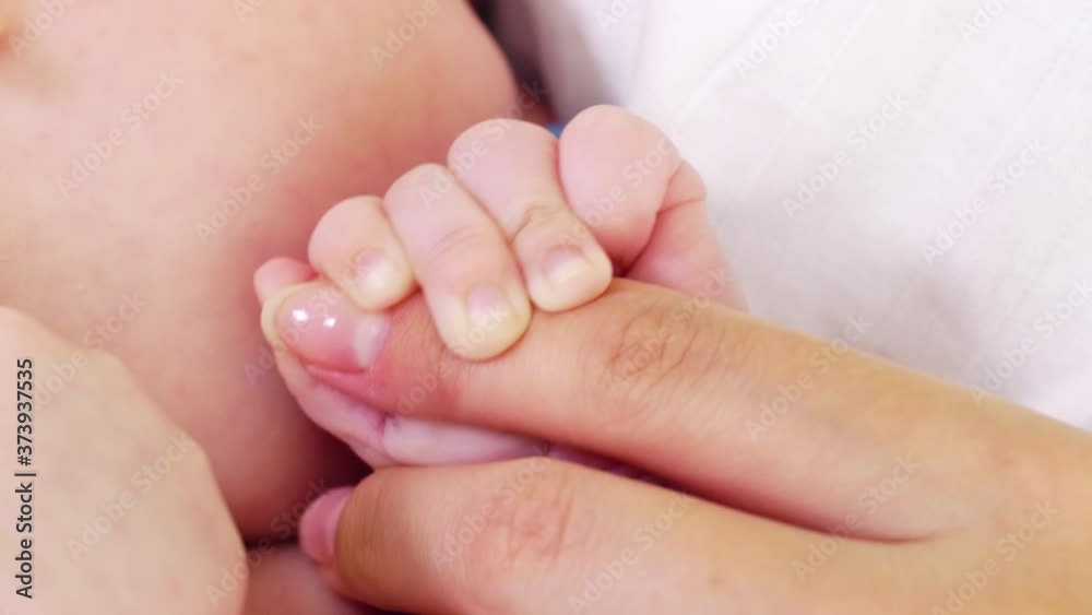 Close up shot of newborn baby holding finger of mother and sucking pacifier Close up shot of newborn baby holding finger of mother and sucking pacifier