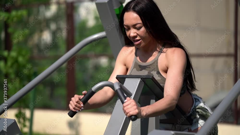 sporty woman is training on open area with public weight machine, lifting leg, workout sporty woman is training on open area with public weight machine, lifting leg, workout