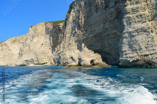 Gray rocks on the blue waters of the Mediterranean Sea in Greece. Motorboat traces on the water