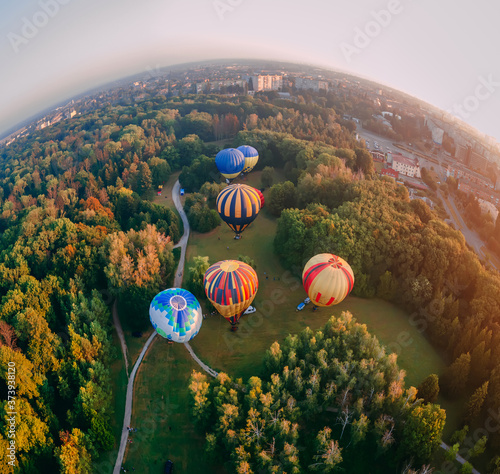 Panoramic air view of hot air ballons prepare for an early morning takeoff from park in small european city