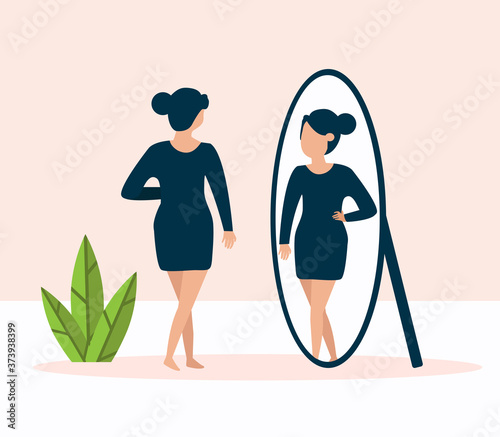 woman standing in front of mirror and looking at reflection looking