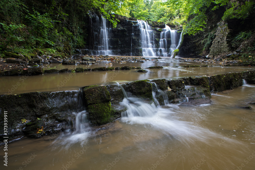 Hidden waterfall in a deep gorge with trickling white water. Forest of Bowland, Ribble Valley, Lancashire