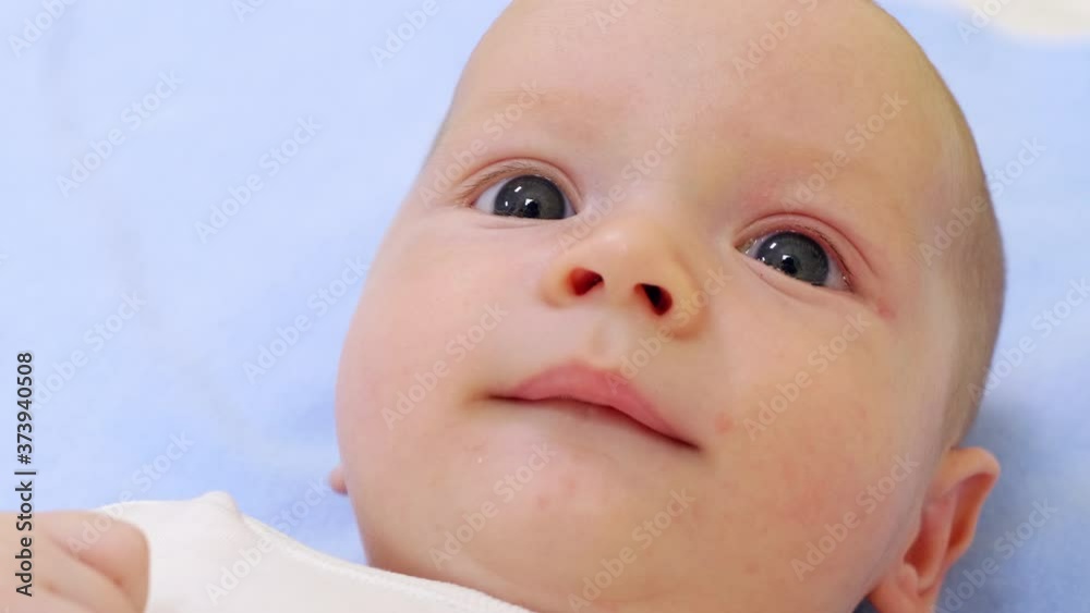 Close up shot of face of adorable newborn baby boy lying on back on bed Close up shot of face of adorable newborn baby boy lying on back on bed