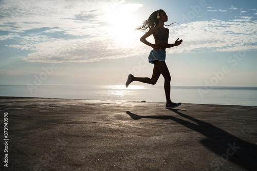 Image of african american girl in headphones running on promenade