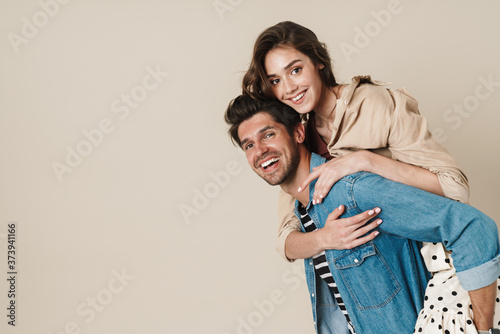 Image of cheerful beautiful couple piggybacking and laughing