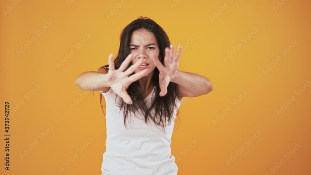 Woman smiling, singing and shaking hair while dancing over orange background Woman smiling, singing and shaking hair while dancing over orange background
