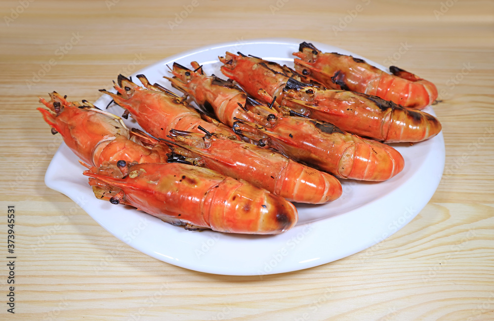 Plate of Flaming Grilled River Prawns Served on Wooden Table Plate of Flaming Grilled River Prawns Served on Wooden Table