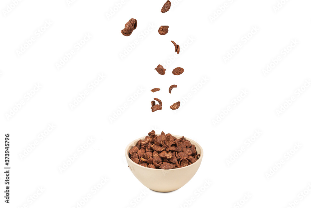 Chocolate corn flakes falling to the white bowl isolated on white. Motion.