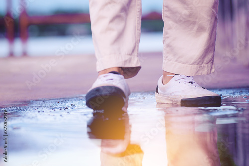 Unrecognizable people wear cloth shoes or sneaker and walking through the floor that contain water spilled (Focus at back leg).