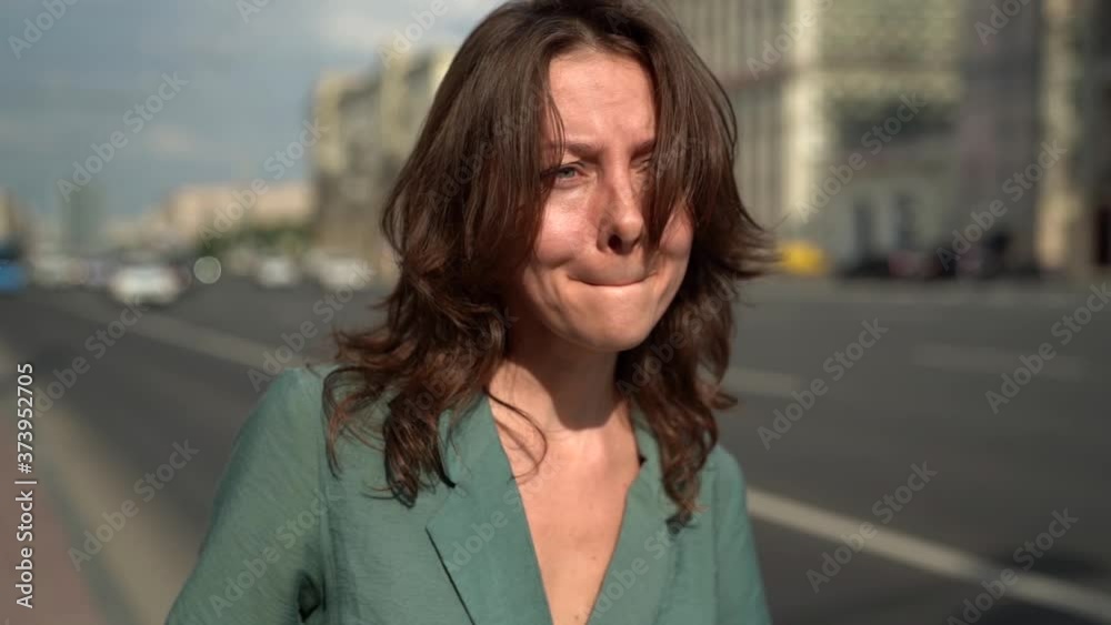 sorrowful woman is crying and going on street, sad face expression, closeup portrait in movement