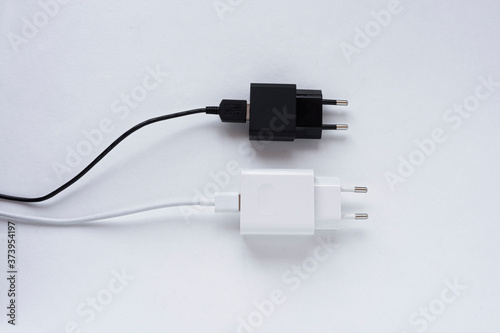 Black and white charger with a plug on a white background, charger with a block, for a smartphone, top view