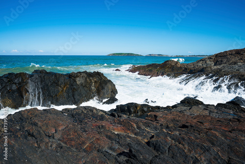 A wave crashes against the rocks at Macauleys Headland, Coffs Harbour coast, New South Wales, Australia.