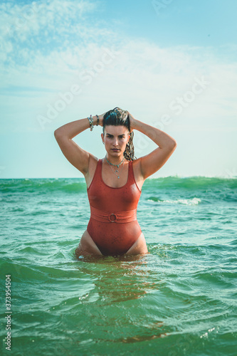 Beautiful young European woman with an orange swimsuit at the sea in Cádiz