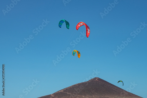 Power kites flying above the mountain, used by kitesurfers to ride the waves at one of the windiest beaches on the island, Montana Roja, El Medano, Tenerife, Canary Islands, Spain photo