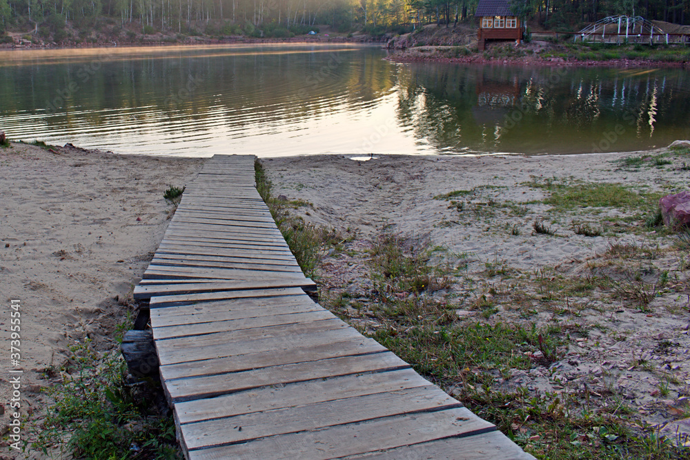 wooden deck leads to the lake water in the morning sun