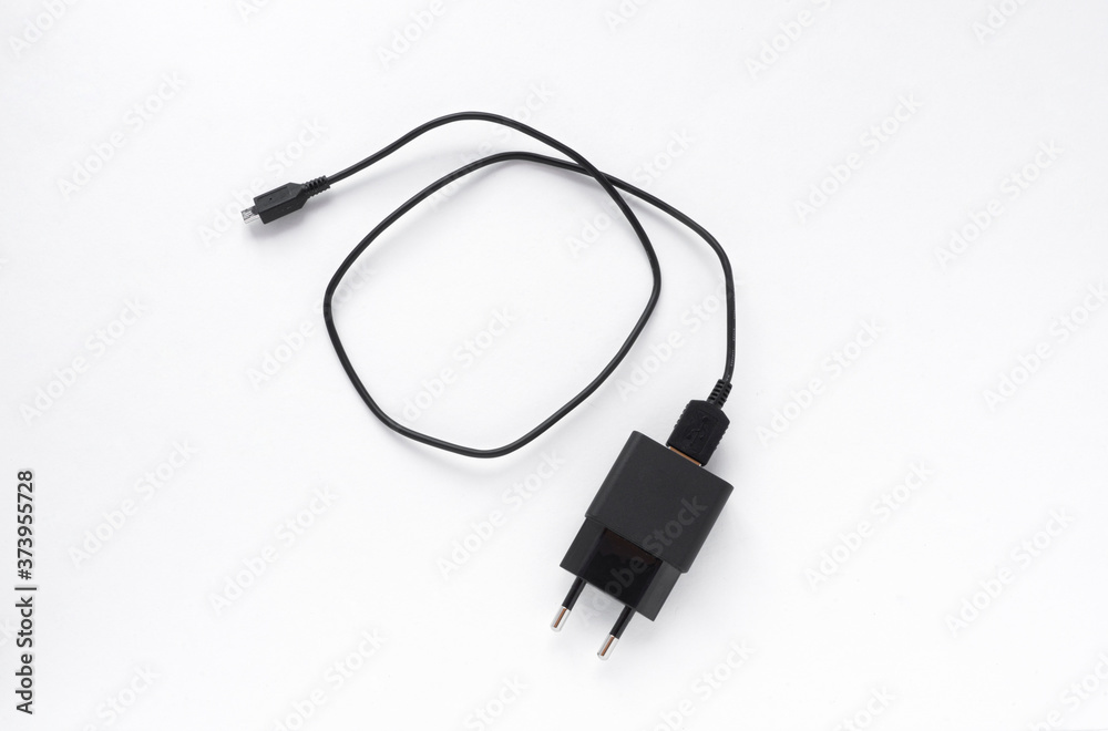 Charger with black plug on white background, charger with block, for smartphone, top view Charger with black plug on white background, charger with block, for smartphone, top view