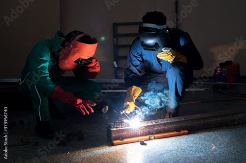 Workers in protective clothing is repairing metal by means of welding, Industrial plant, Metal welder.