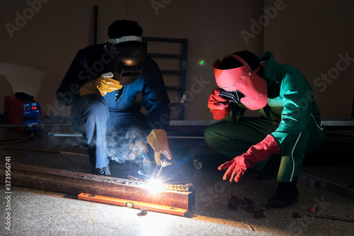 Workers in protective clothing is repairing metal by means of welding, Industrial plant, Metal welder.