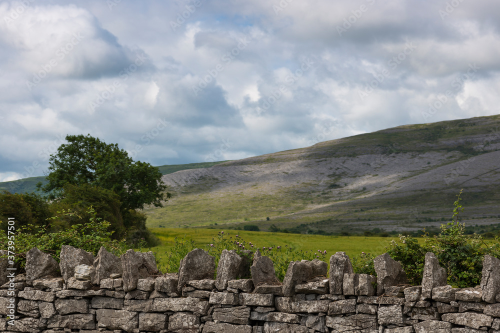 Irish dry stone wall with the unusual hills of 'the Burren' region of County Claire, Republic of Ireland.